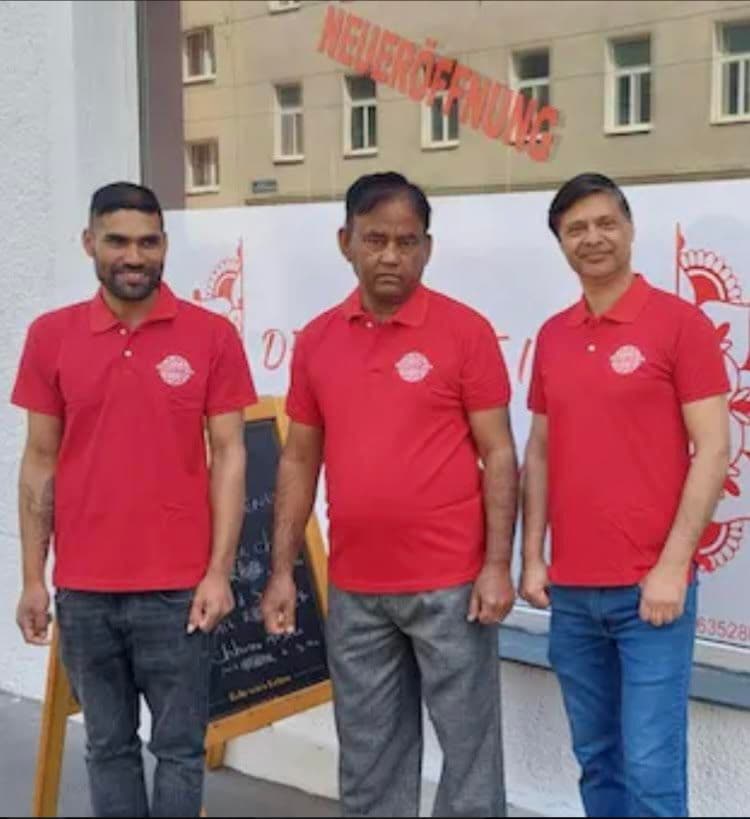 Three employees standing in front of the restaurant wearing red dress